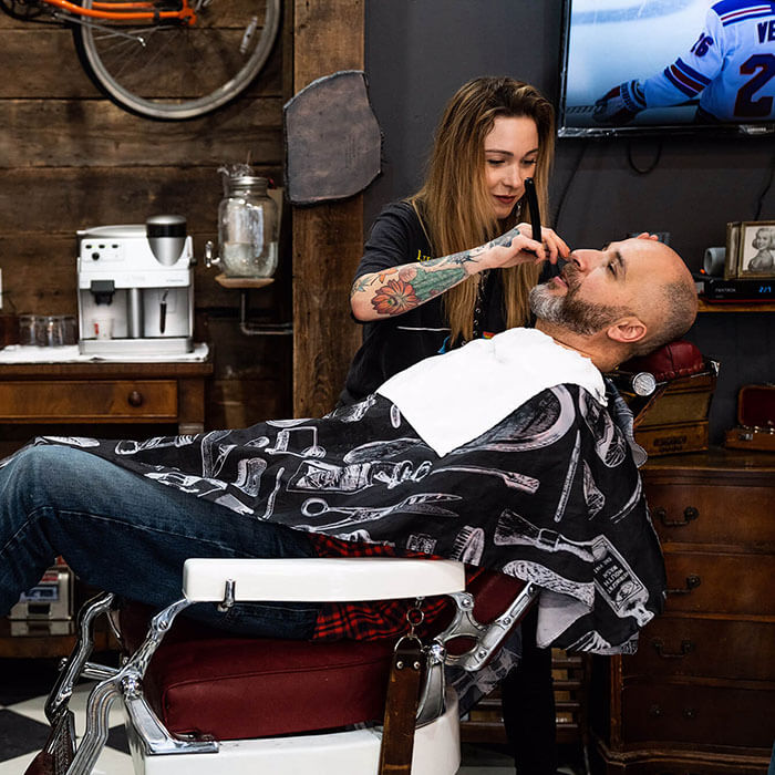 Woman giving man beard trim and line up